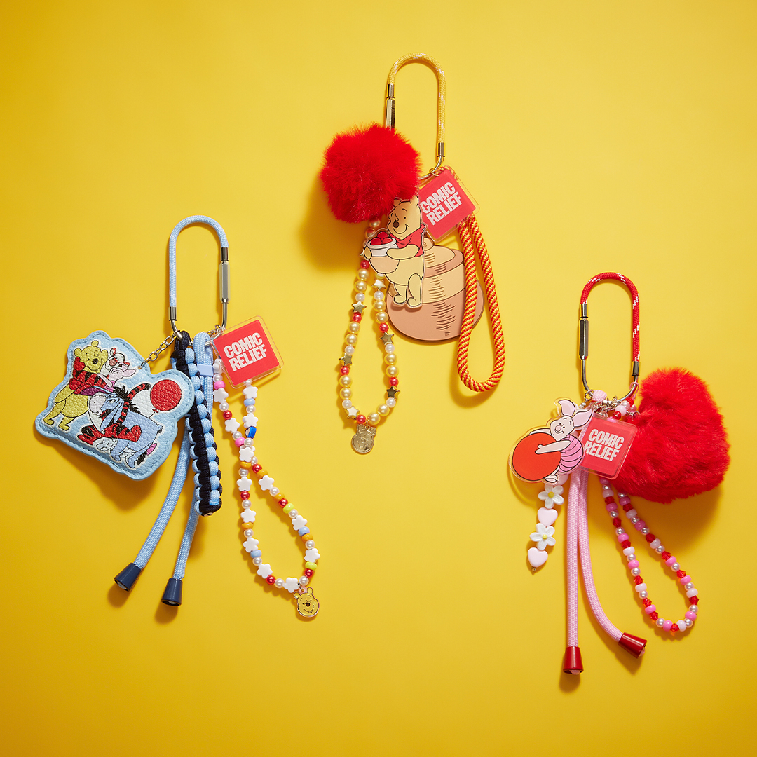 Three Winnie the Pooh–themed bag charms displayed against a bright yellow background. Each charm hangs from a carabiner and features colourful beaded loops, Comic Relief tags, and fluffy red pom poms, with designs inspired by Pooh, Tigger, and other classic motifs.